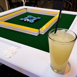Pineapple mocktail drink on a Mahjong table cup holder.  The Mahjong style Riichi table is ready for four players to begin playing.